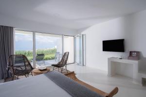 a bedroom with a bed and chairs and a television at Sul Villas & Spa - Azores in Lagoa