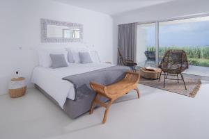 a bedroom with a bed and a chair and a window at Sul Villas & Spa - Azores in Lagoa