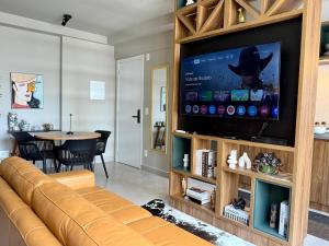 a living room with a couch and a flat screen tv at Studio moderno e confortável no Marista in Goiânia