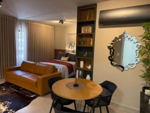a living room with a couch and a table and a bed at Studio moderno e confortável no Marista in Goiânia