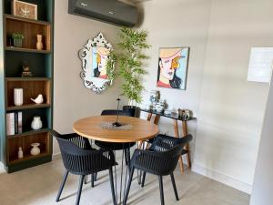 a dining room with a wooden table and black chairs at Studio moderno e confortável no Marista in Goiânia +9 photos