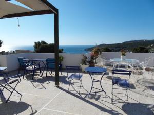 a patio with tables and chairs and a view of the ocean at Eri Studios in Agia Marina Aegina