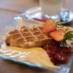 a plate with waffles and strawberries on a table at Hotel Eifeltor in Mechernich