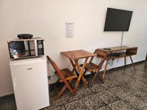 a microwave sitting on top of a refrigerator next to a table at Suíte Rodoviária no centro de Arraial in Arraial do Cabo