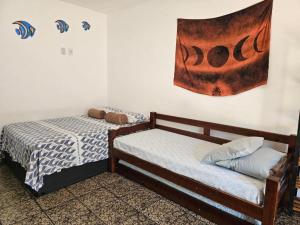 a bedroom with two beds and a painting on the wall at Suíte Rodoviária no centro de Arraial in Arraial do Cabo