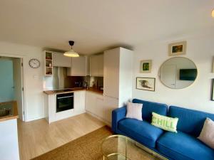 a living room with a blue couch and a kitchen at Modern 2-Bed Apartment with Off-Street Parking in Chiswick in London