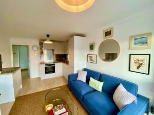 a living room with a blue couch and a kitchen at Modern 2-Bed Apartment with Off-Street Parking in Chiswick in London +6 photos