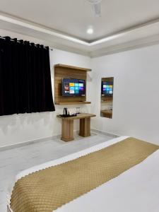 a room with a bed and a table and a tv at Shri Prem Sharnam - By The Aureo Hotels in Vrindāvan