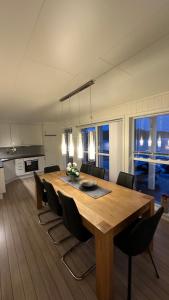 a kitchen and dining room with a wooden table and chairs at Heggøy rorbuer in Heggøyni