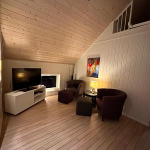 a living room with a flat screen tv and furniture at Heggøy rorbuer in Heggøyni
