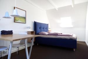 a bedroom with a blue bed and a table at Gertruds Petit Hotel in Odense +3 photos