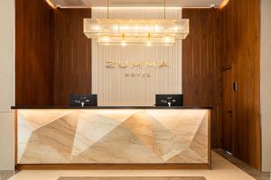 a lobby with a counter with a sign on a wall at ZUMMA Hotel Almaty in Almaty