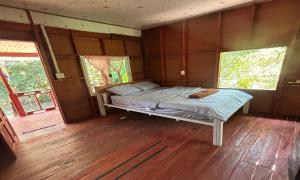a bed in a room with wooden floors and windows at Duangkeaw Simple House in Phra Ae beach