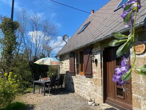 a table and chairs outside of a house with an umbrella at The Bakery in Beauficel