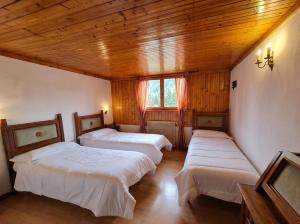 three beds in a room with wooden ceilings at Garni Pirata in Cavareno +7 photos