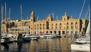 a large building with a bunch of boats in the water at Suite Victory Authentic Maltese Duplex in Birgu in Birgu