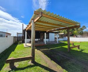 a wooden pergola sitting on top of a grass field at Maridalba 1 in La Coronilla