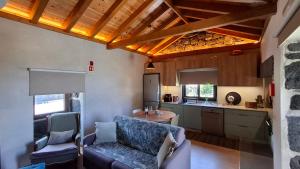 a kitchen with a couch and chairs in a room at Refúgio dos Capelinhos - Villa e Suites in Norte Pequeno