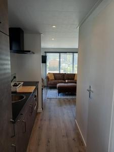 a kitchen with a living room with a couch at Luxe chalet voor gezinnen in familiepark Goolderheide met openlucht zwembaden en ruim overdekt terras 24m2 in Bocholt