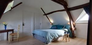a bedroom with a blue bed and a wooden floor at Retour en Baie in Pendé