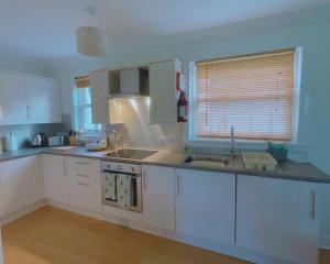 a kitchen with white cabinets and a sink and a window at Buttercup Cottage in Killean