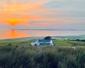 a painting of a house in a field with a sunset at Buttercup Cottage in Killean +13 photos