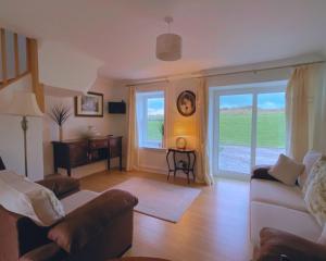 a living room with a couch and a large window at Buttercup Cottage in Killean