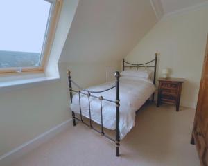 a bedroom with a bed next to a window at Buttercup Cottage in Killean
