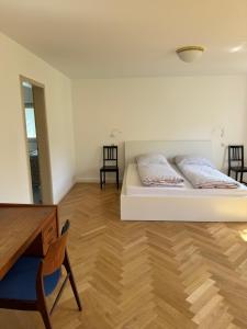 a bedroom with a white bed and a wooden floor at Greenhouse in Fellbach