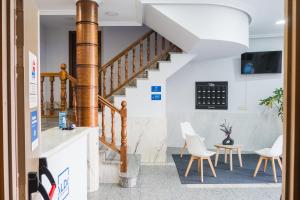 ein Flur mit einer Treppe, Stühlen und einem Tisch in der Unterkunft Alda Arteixo in Vilarrodis