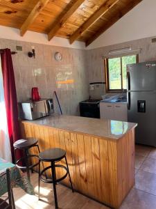 a kitchen with a counter with stools and a refrigerator at Cabañas arca 2 in Pucón