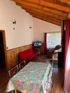 a living room with a table and a red couch at Cabañas arca 2 in Pucón