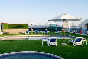 a swimming pool with chairs and an umbrella at Luxe Grand Hotel in Dubai