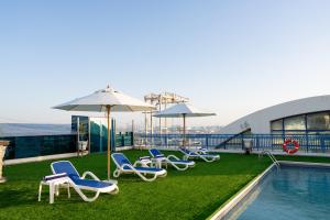 a group of chairs and umbrellas next to a pool at Luxe Grand Hotel in Dubai