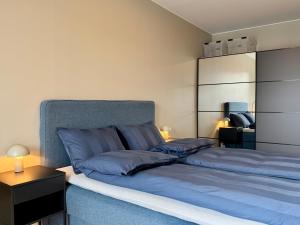 a bedroom with a bed with blue sheets and a night stand at Apartment by Kokstad tram in Bergen