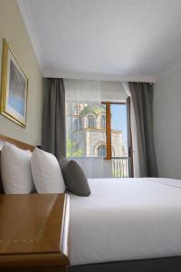 a bedroom with a large white bed and a window at Hotel Turist - City Center in Skopje +26 photos