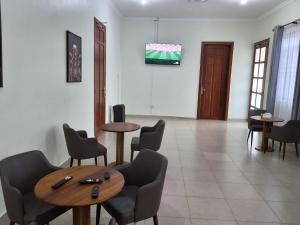 a waiting room with tables and chairs and a tv at Yigs Motel in Iringa