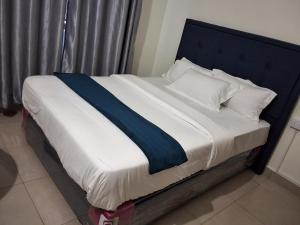 a bed with a blue headboard and white sheets and pillows at Yigs Motel in Iringa