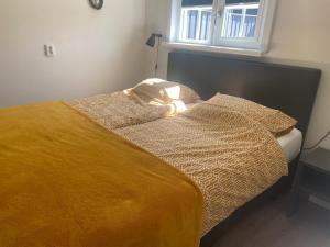 a bed with a yellow blanket and two pillows at Zon en Zee 2 personen in Westkapelle
