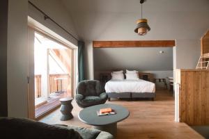 a bedroom with a bed and a chair and a table at Les Cèdres - Hôtel - Restaurants - Spa in Saint-Sorlin-dʼArves