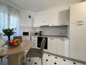 a kitchen with white cabinets and a table with a bowl of fruit at Villa ARINA - Apartments 20 m from Beach, Tucepi in Tučepi