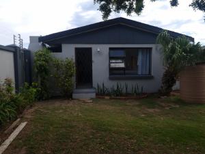 a small white house with a window and a yard at 15 on 11th Summerstrand in Summerstrand