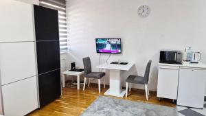 a kitchen with a table and chairs and a tv at Apartman IDEA in Zrenjanin