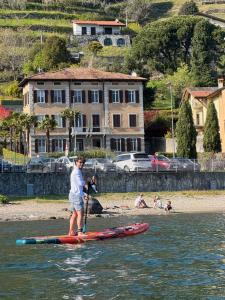 a man standing on a paddle board in the water at Immobillario - Domus Palmae in Domaso