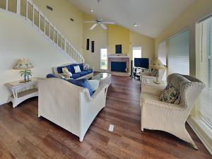 a living room with wicker chairs and a staircase at Whispering Sands Beachfront in Galveston