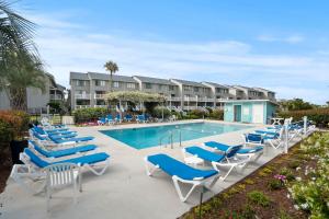 a pool with blue and white lounge chairs and a resort at Oceanfront St Helena Island Condo w/ Beach Access! in Oceanmarsh Subdivision