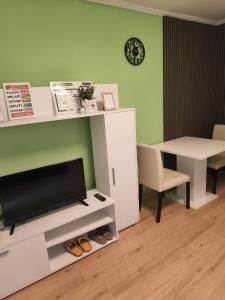 a living room with a tv and a desk and a table at Apartman Andjela 1 in Vrdnik