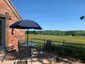 a patio with a table and chairs and an umbrella at 3 or 4 Bed 2 Bath Cosy Rural Barn Conversion-Parking in Beoley