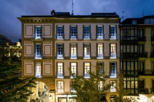 een groot geel gebouw met lichten aan bij Legazpi Doce Rooms & Suites in San Sebastian