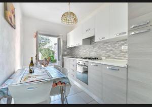 a kitchen with white cabinets and a table with chairs at Casa Gaia a soli 20 mt dal mare in Pomonte